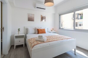 A bedroom with a bed, bedside tables, a window, and wall art. - Hermes 2-BR Apt. & Balcony in Larnaca (Larnaca)