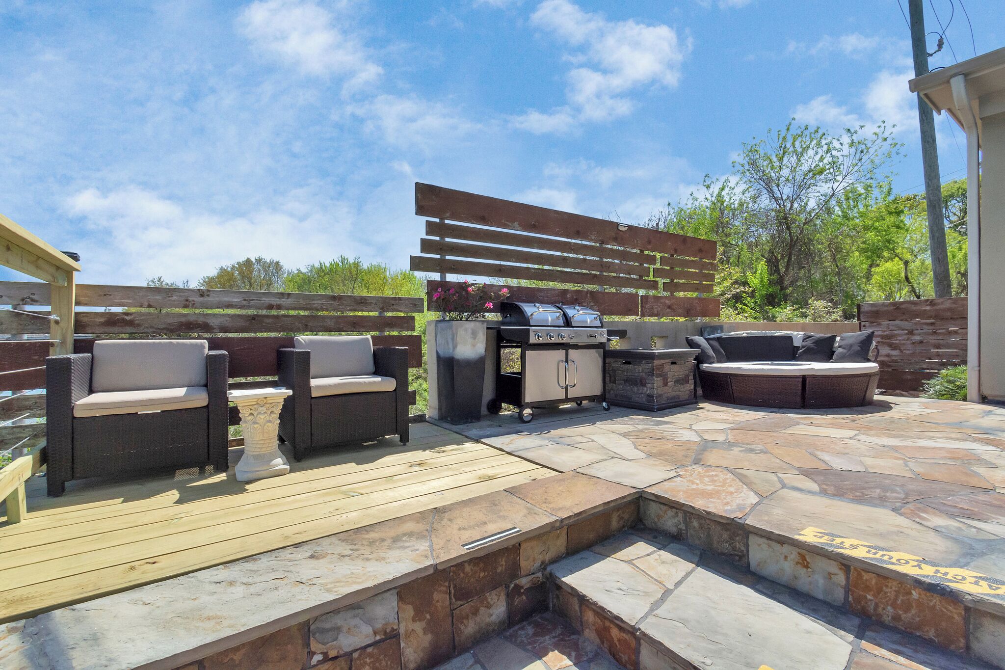 Une terrasse extérieure avec un barbecue, des sièges et une plateforme en pierre.