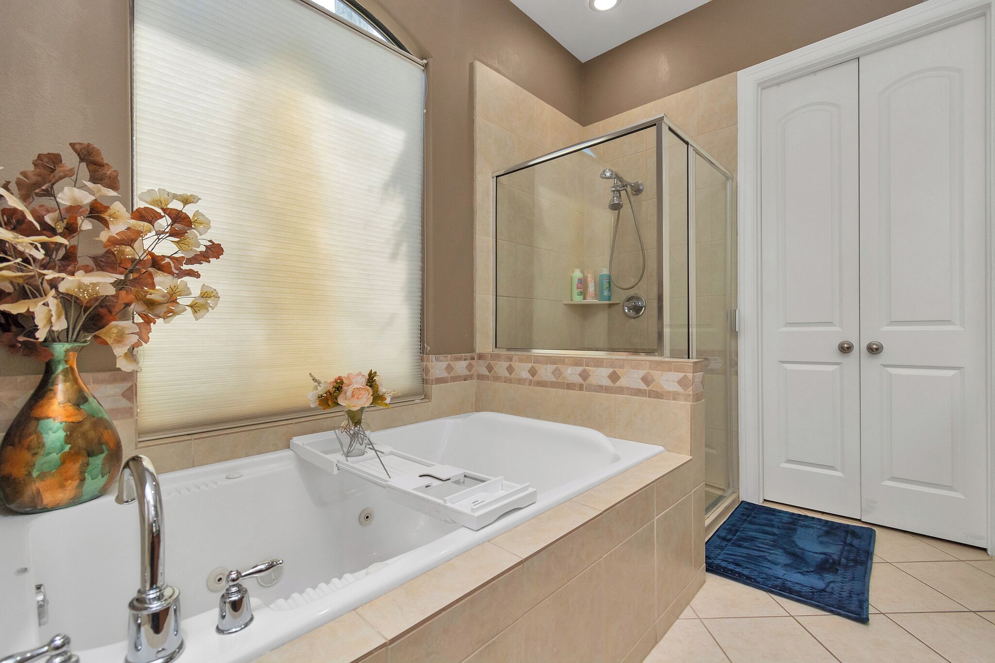 A bathroom with a bathtub, a shower, a mirror, and a white door.