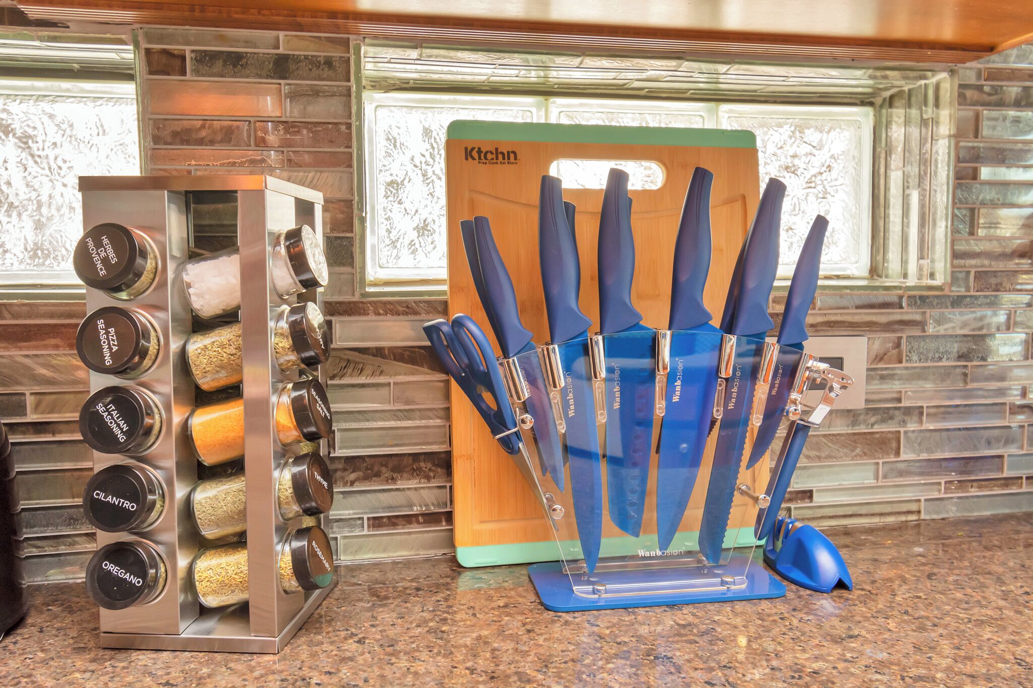 A kitchen with a spice rack, a knife block, and a window with a view of the outside.