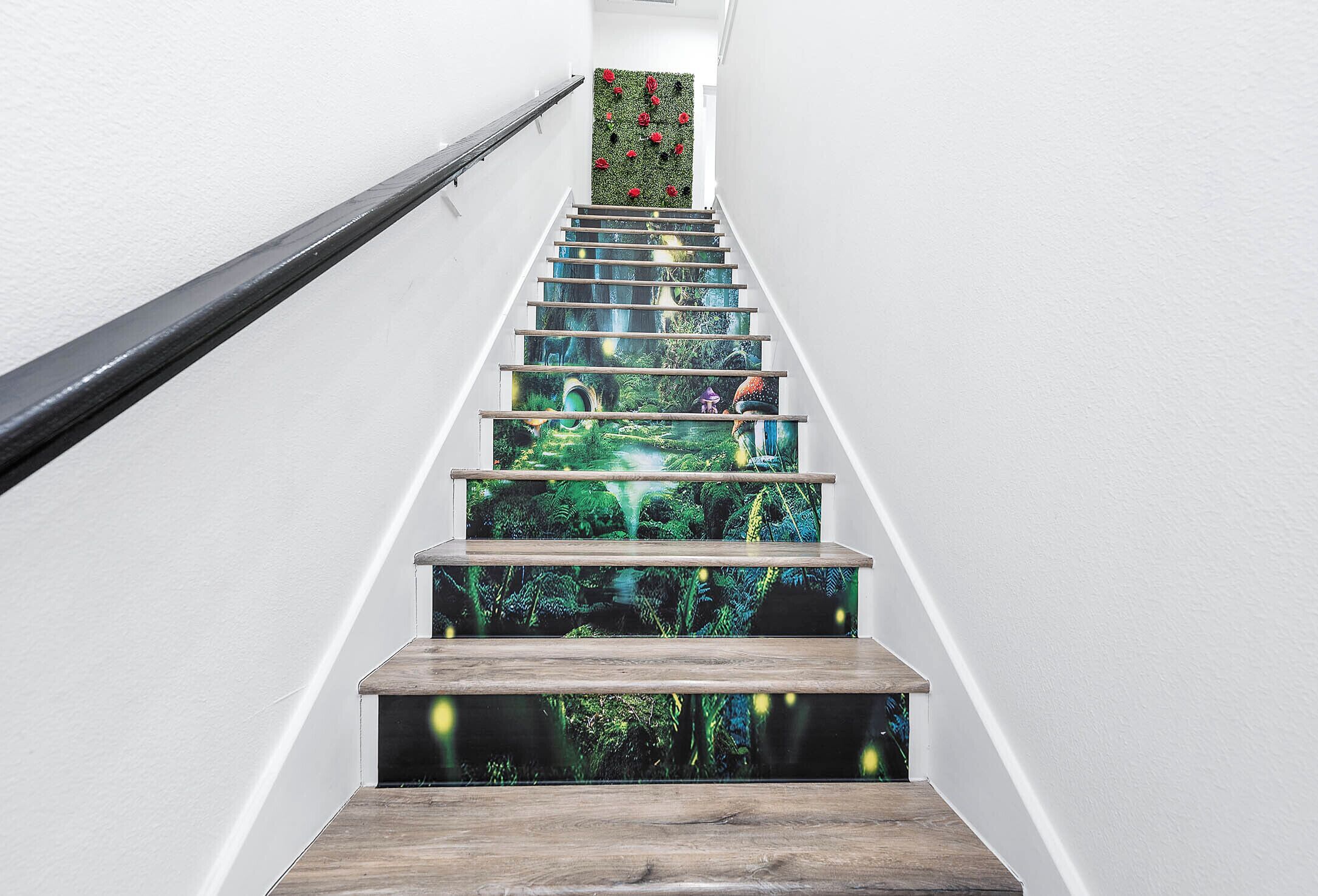A staircase with a wooden handrail and steps featuring a forest-themed design.