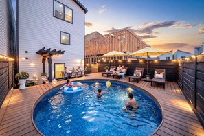 Ein Pool mit Holzboden, umgeben von einem Holzzaun, und ein Gebäude mit weißer Fassade.
