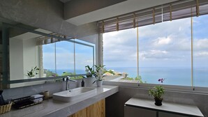 Uma casa de banho moderna com uma janela grande, uma pia, um espelho e armários de madeira.