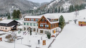 A hotel with a wooden facade, multiple balconies, and a snow-covered landscape. - Centrally located and at the ski slope. (Hohentauern)