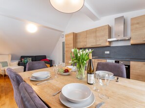 Una cocina moderna con armarios de madera, una mesa de comedor preparada con platos, vasos y una botella de vino.