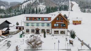 A building with a cafe and restaurant sign, surrounded by snow-covered landscape and mountains. - Centrally located and at the ski slope. (Hohentauern)