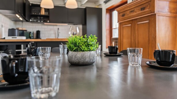 A modern kitchen with a central island, pendant lights, and wooden cabinets.