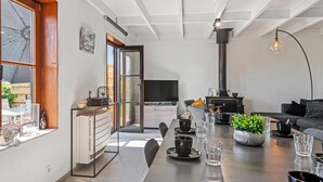 A modern kitchen with a dining area, a black stove, and a TV.