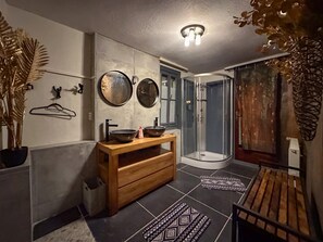 A bathroom with a wooden vanity, two round mirrors, a glass shower enclosure, and patterned floor mats. - Cosy, complete house in the centre of Cochem (Cochem)