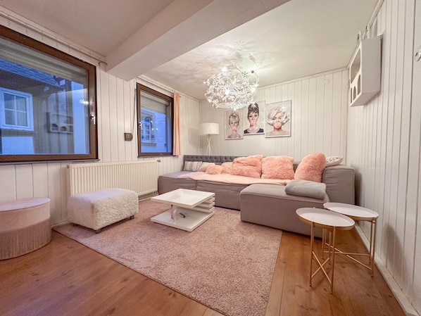 Ein modernes Wohnzimmer mit einer Couch, Hocker, Couchtisch und Beistelltischen.