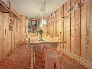 A wooden-paneled room with a dining table, chairs, a vase with flowers, and shelves with items. - Cosy, complete house in the centre of Cochem (Cochem)