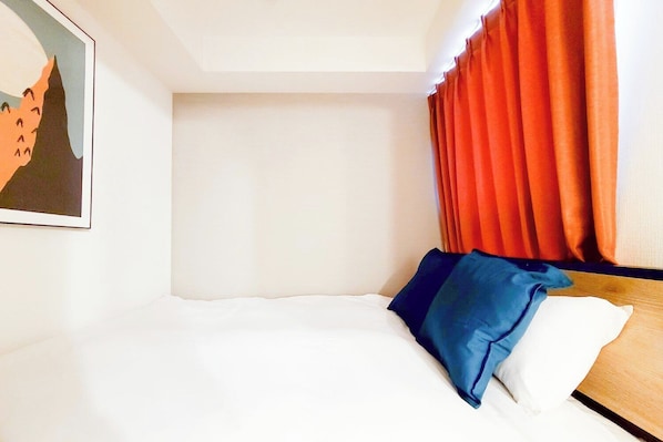A hotel room with a bed, a painting on the wall, and orange curtains. - BLUE Motomachi (Osaka)