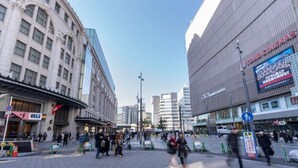 Vilkkaalla kaupunkiaukiolla on moderneja rakennuksia, kuten elokuvateatteri, sekä perinteinen rakennus, jossa on klassinen arkkitehtuuri.
