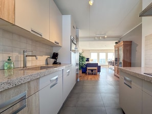 A modern kitchen with a built-in oven, a coffee machine, and a dining area with a table and chairs. - Spacious holiday home by the Neuastenberg lifts (Neuastenberg)