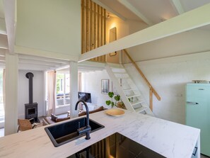 A modern kitchen with a built-in sink, a stove, and a staircase leading to an upper level. - Scandinavian holiday home with a large garden (Warmenhuizen)