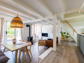 A modern living room with a dining area, a staircase, and a kitchen. - Scandinavian holiday home with a large garden (Warmenhuizen)