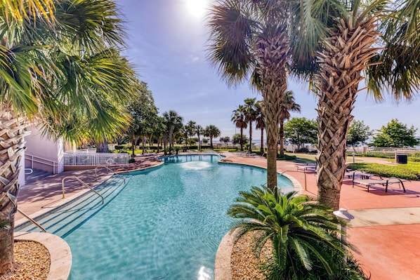A swimming pool surrounded by palm trees and a white fence.