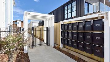 A modern building with a gated entrance, a series of mailboxes, and a clear sky.