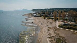 Eine Küstenlandschaft mit Sandstrand, einer Straße und einer Reihe von Gebäuden.