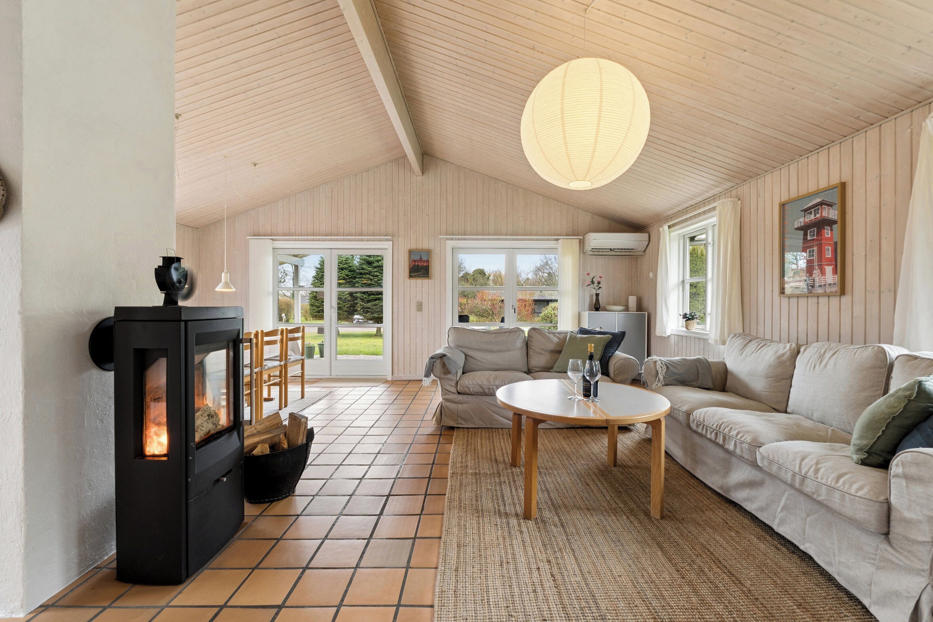Ein gemütliches Wohnzimmer mit Kamin, einer Couch, einem Couchtisch und einem großen Fenster.