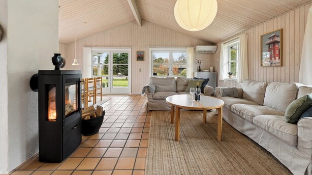 Ein gemütliches Wohnzimmer mit Kamin, einer Couch, einem Couchtisch und einem großen Fenster.