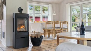 Ein gemütliches Zimmer mit Kamin, Esstisch, Stühlen und großen Fenstern.