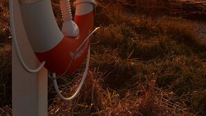 A lifebuoy attached to a pole by the seaside during sunset.