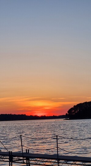 A sunset over a calm body of water with a dock in the foreground. - Close to water – calm, spa and comfort (Skibby)