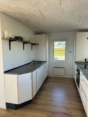 A modern kitchen with white cabinets, a black countertop, and a window with a view of greenery. - Lovely holiday home with beautiful views (Sydals)