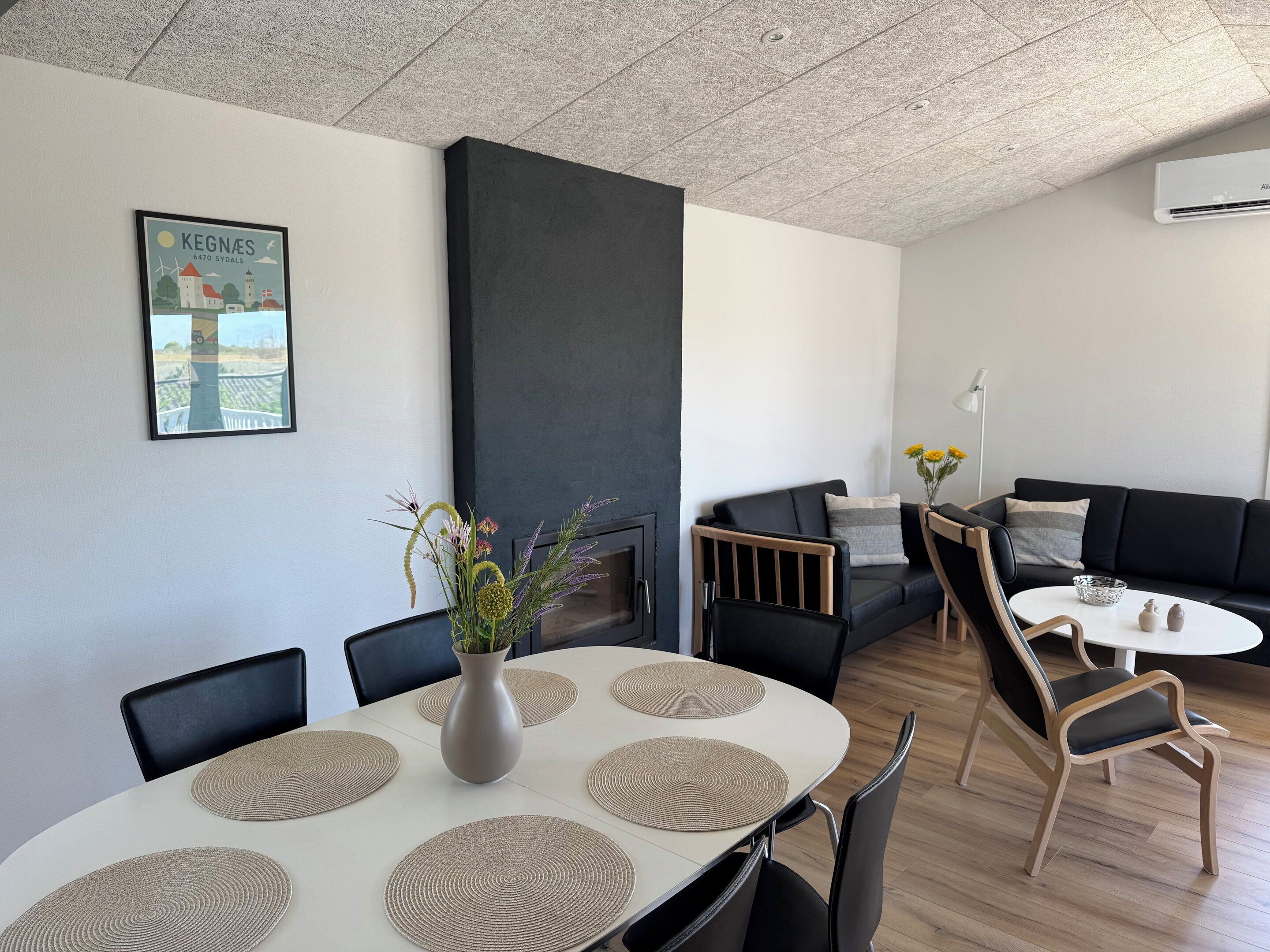 Et moderne interiør med spisebord, stole, sofa og pejs.
