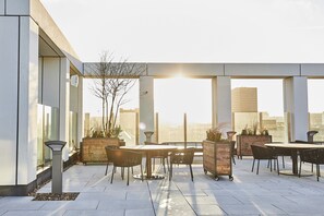 An outdoor patio with tables and chairs, potted plants, and a cityscape view. - Luxe City -Luxury Manchester City Stay - Skyline Views (Manchester)