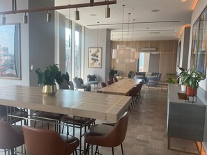 A modern dining area with a long table, multiple chairs, and potted plants. - Luxe City -Luxury Manchester City Stay - Skyline Views (Manchester)