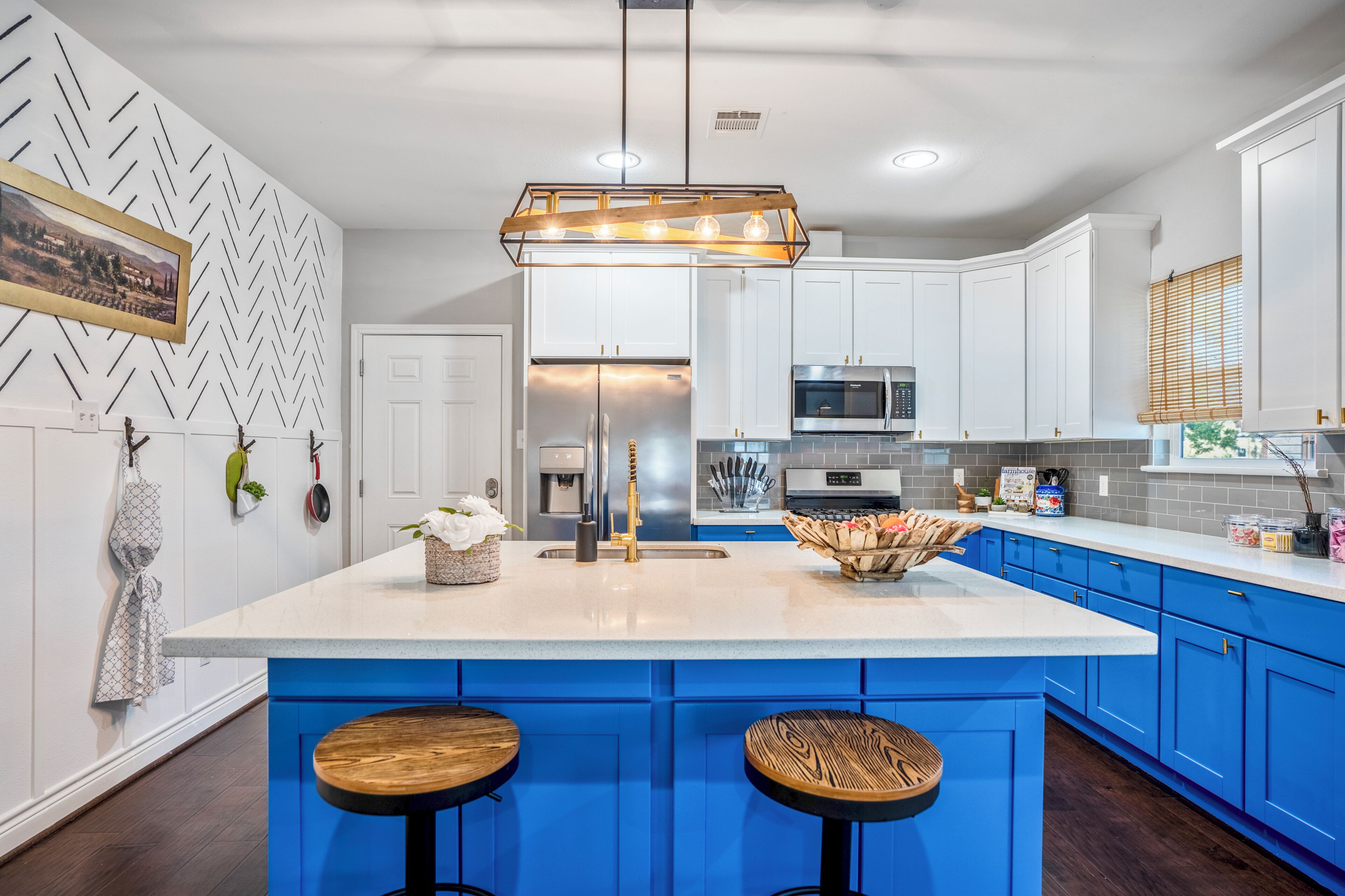 A modern kitchen with a central island, blue cabinets, and a pendant light.