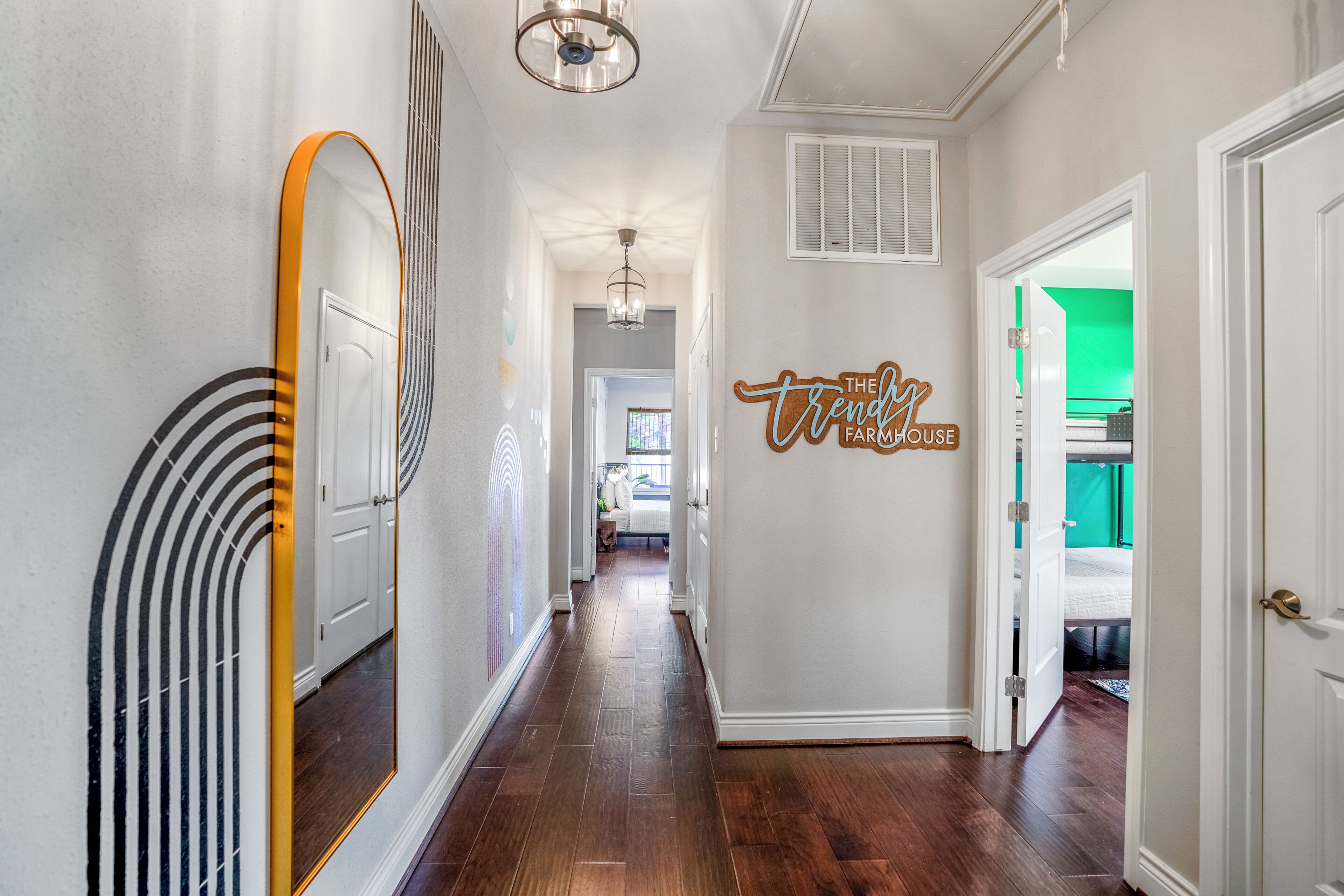 A hallway with a mirror, a ceiling fan, and a wall sign.