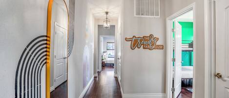 A hallway with a mirror, a ceiling fan, and a wall sign.