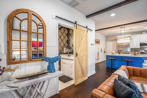 Una cocina moderna con una isla central, una puerta corredera estilo granero y un espacio de sala de estar acogedor con un sofá de cuero.