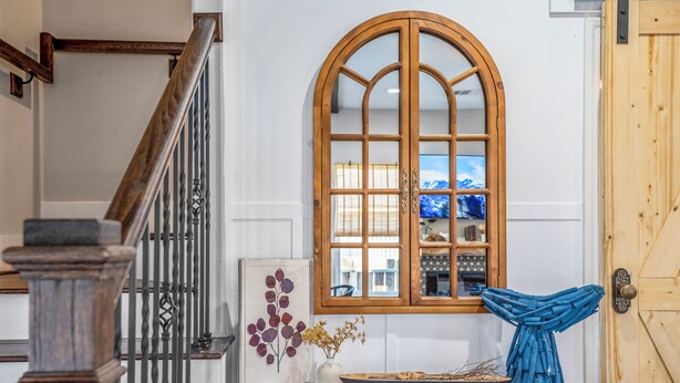 A staircase with a wooden handrail, a window with a wooden frame, and a door with a wooden panel. - Empress Garden Villa (Houston)
