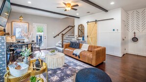 A living room with a brown leather sofa, a round coffee table, and a large mirror. - Empress Garden Villa (Houston)