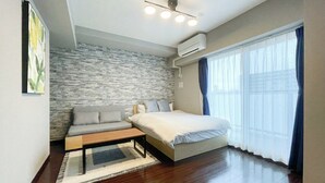 Een moderne slaapkamer met een stenen muur, een bed, een slaapbank en een bankje.