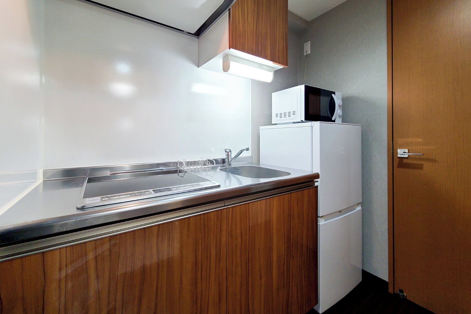 A compact kitchenette with a microwave, refrigerator, and sink.