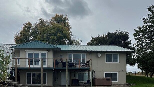 Een tweelaags huis met een overdekte veranda, een schotelantenne en een oprit van grind.
