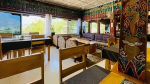 A room with a large window, wooden furniture, and a decorative wall with traditional patterns. - Sinchula Villa Resort (Paro)