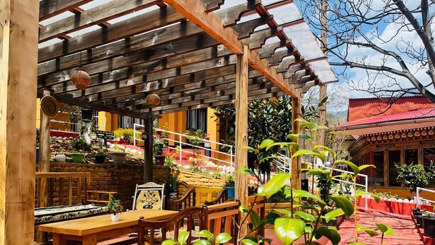 A wooden pergola with a brick floor, a wooden bench, and potted plants. - Sinchula Villa Resort (Paro)