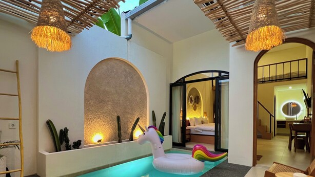 Una zona de piscina con un unicornio flotante, una silla de descanso y un comedor.
