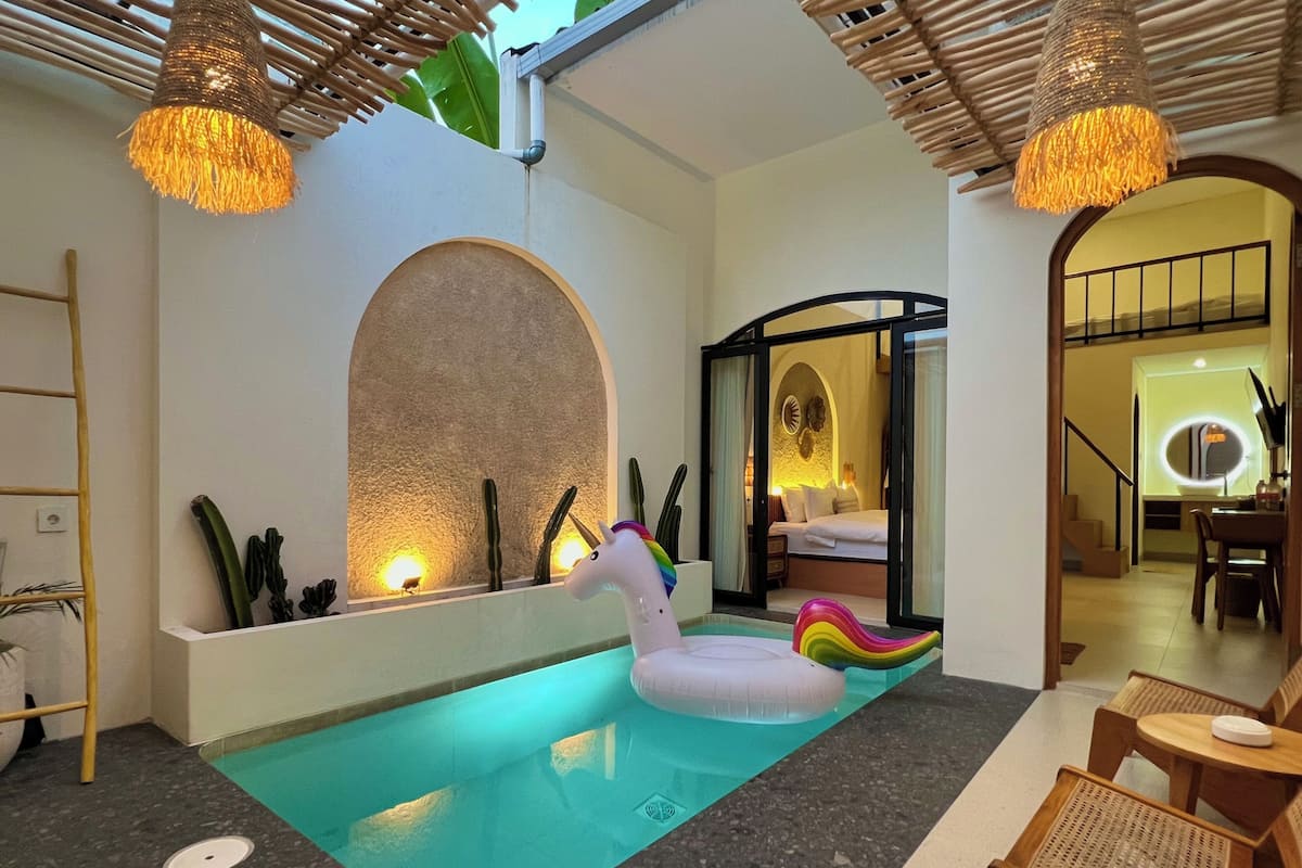 Una zona de piscina con un unicornio flotante, una silla de descanso y un comedor.
