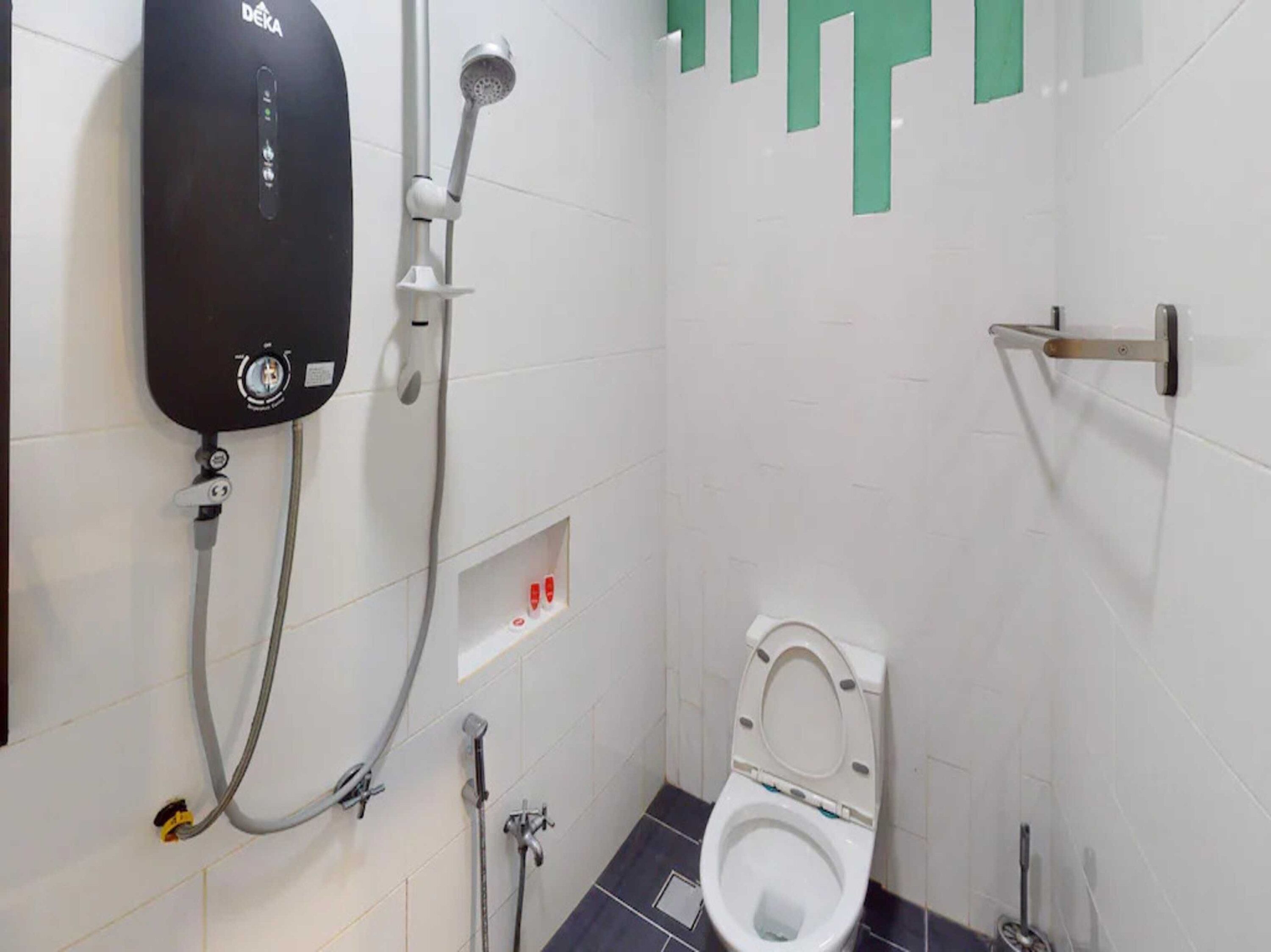 A small, modern bathroom with a shower, toilet, and a wall-mounted heater.