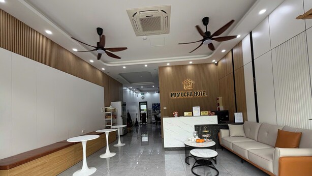 A hotel lobby with a reception desk, seating area, ceiling fans, and a polished floor. - Mimocha Hotel - Hoa Lu Ancient Town Ninh Binh (Hoa Lu)