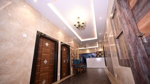 Un hall de hotel con mostrador de recepción, puertas de madera y un candelabro.