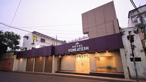 Un hotel llamado 'Hotel Venkatesh' con un letrero sobre la entrada, una puerta cerrada y una escalera visible que conduce a la entrada.