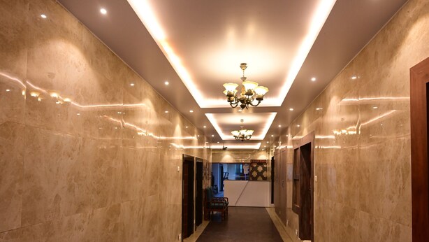 Un pasillo con piso de mármol, iluminación empotrada y un candelabro.